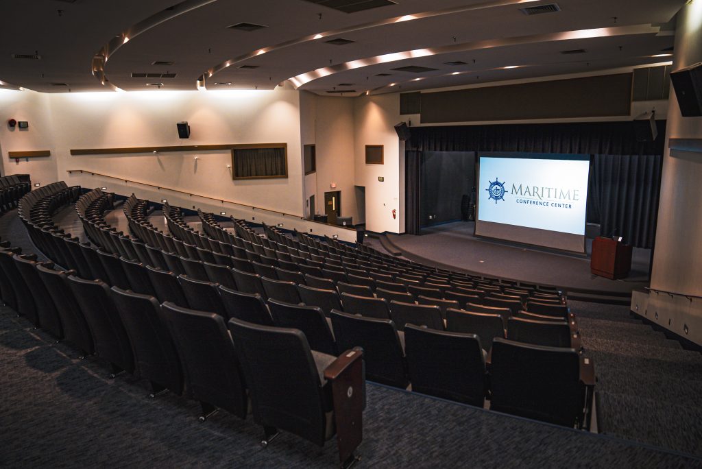 an auditorium with rows of seats and a large screen that says maritime conference center